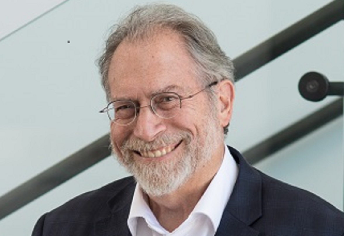 얼굴 사진을 찍기 위해 웃고 있는 남자. 그는 양복을 입고 안경을 쓰고 있다.