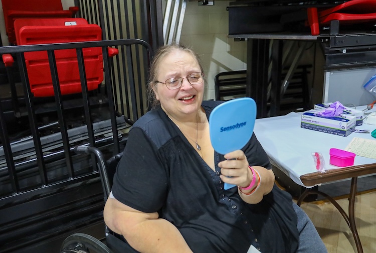 환자는 휴대용 거울로 자신을 바라보며 미소를 짓습니다.