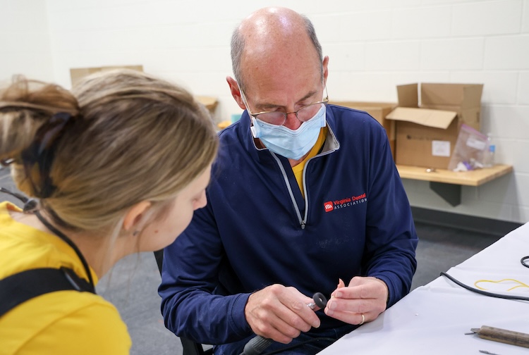 학생이 지켜보는 가운데 치과 의사가 부분 틀니 작업을 하고 있습니다.