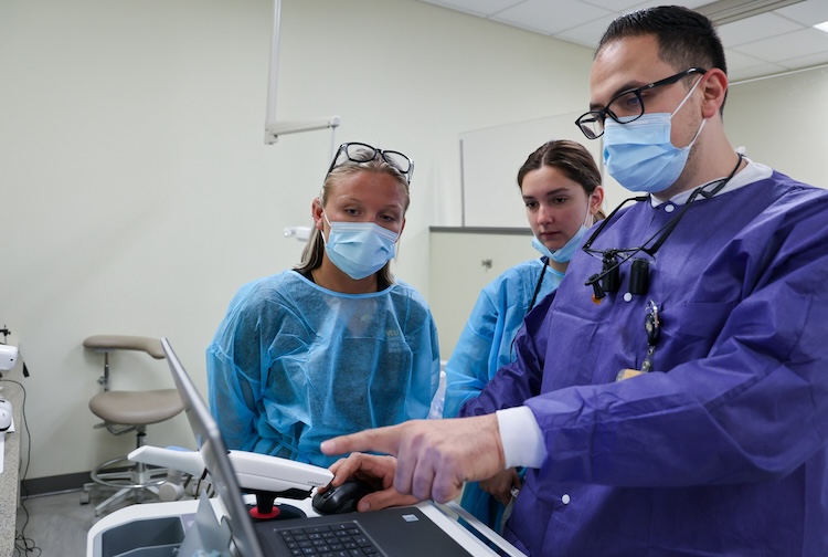 치과의사가 컴퓨터 화면의 이미지를 가리킨다