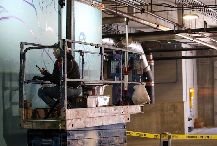 엘리베이터에 앉아 벽화 작업을 하고 있는 여자