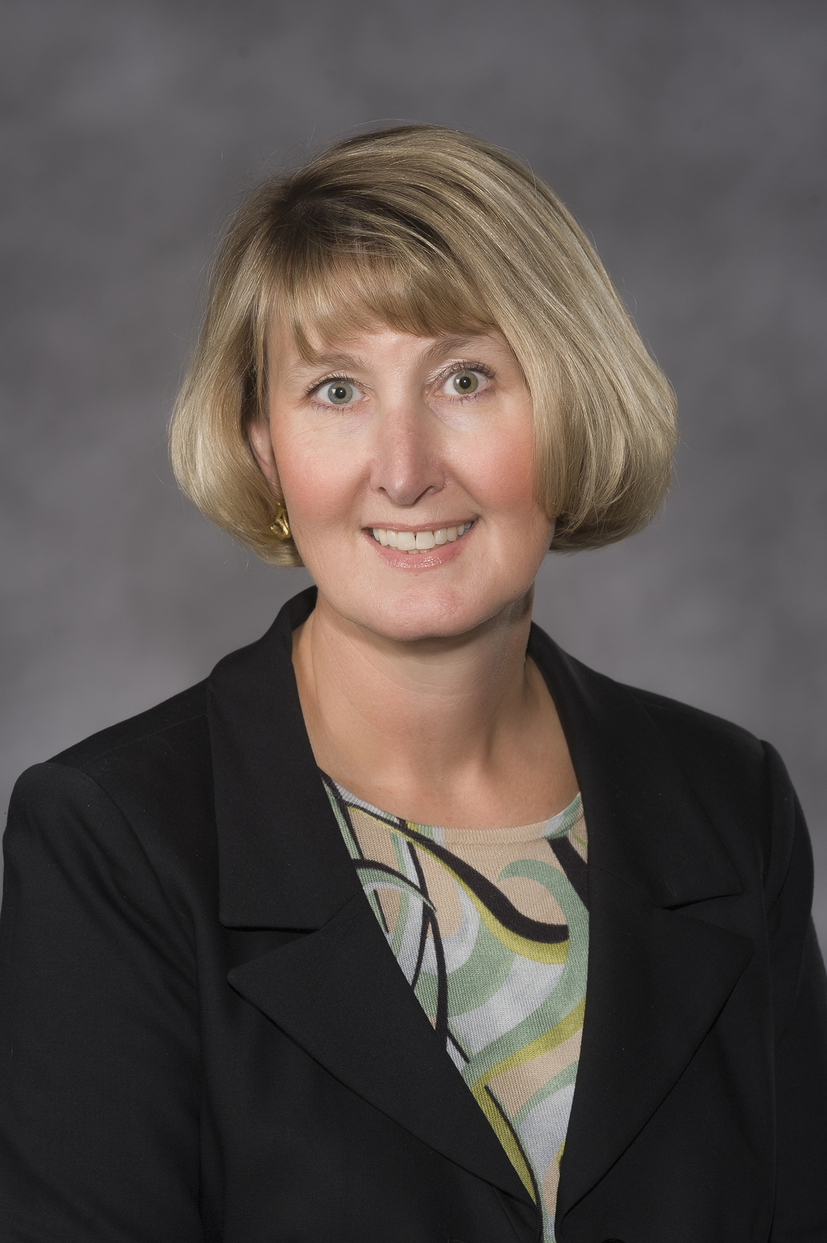 박사. 구드는 검은색 양복 재킷과 녹색 무늬 셔츠를 입고 있습니다.