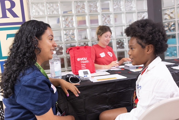 실험실 가운을 입은 소년이 Teach BP의 일환으로 Pauley 심장 센터 팀원과 대화하고 있습니다.