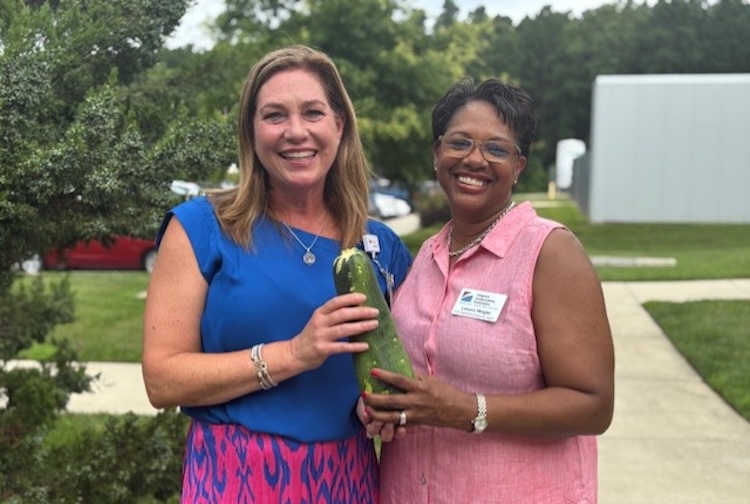 두 여자가 신선한 호박을 들고 정원 앞에서 포즈를 취하고 있습니다.