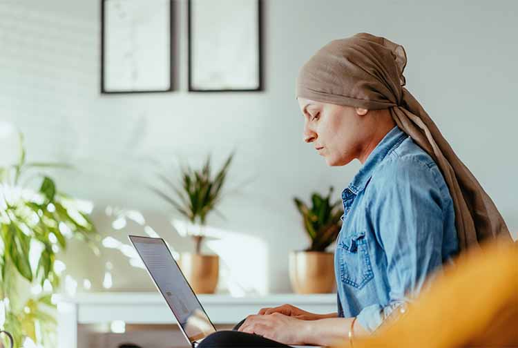 암에 걸린 여성이 노트북을 보고 있습니다