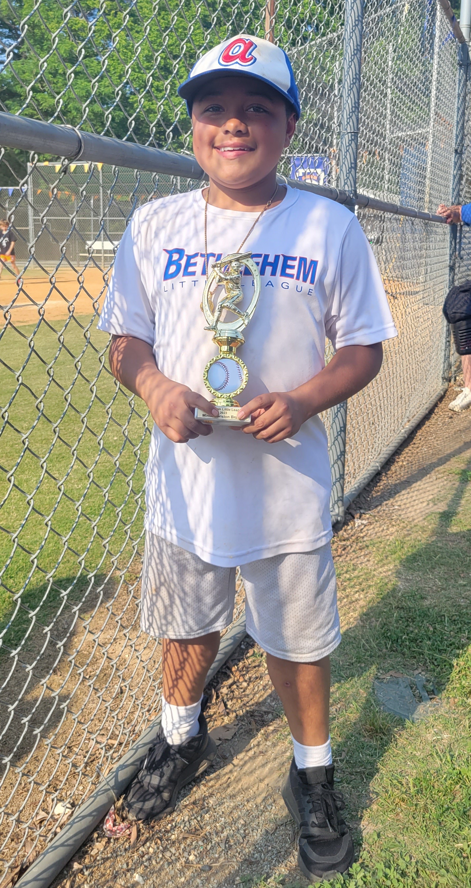 리틀 리그 야구 유니폼을 입고 웃고 있는 어린 소년.