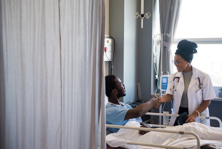 병실에서 남성 환자가 여성 의사와 악수를 하고 있습니다.