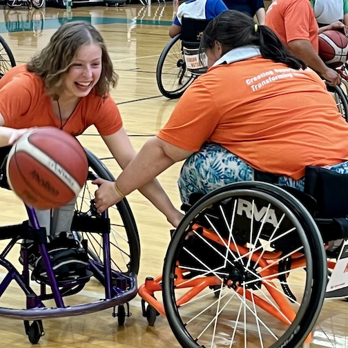 웃으면서 휠체어를 타고 농구를 하는 여성들