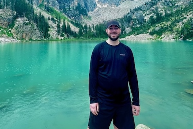 조이는 큰 산과 호수 앞에 서 있습니다.