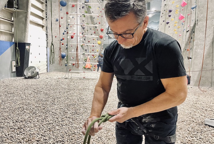 남자는 암벽 등반 벽에 올라갈 준비를 하면서 손에 묻은 분필을 닦습니다.