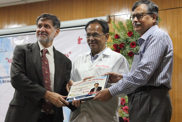 세 남자가 큰 팻말을 들고 웃고 함께 서있습니다.