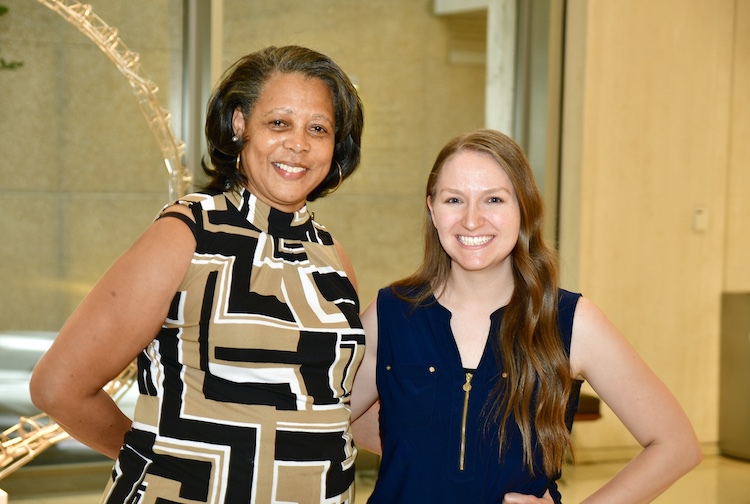 두 여자가 나란히 서서 팔짱을 끼고 웃고 있습니다.