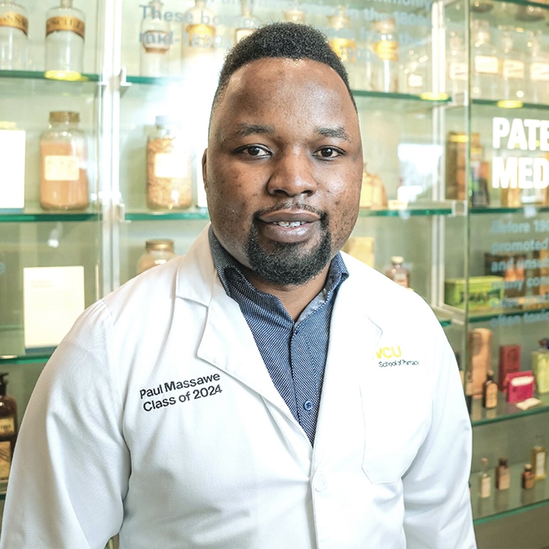 약국 흰색 가운을 입은 청년이 카메라를 향해 미소짓고 있습니다.