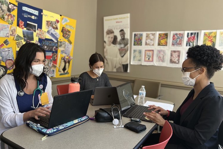 세 명의 여학생이 테이블 주위에 앉아 작업하고 있습니다. 그들은 리치몬드 건강 및 웰니스 프로그램의 일부입니다.