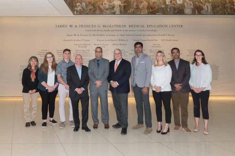 비즈니스 복장을 입은 사람들이 사진을 찍기 위해 함께 서 있습니다.