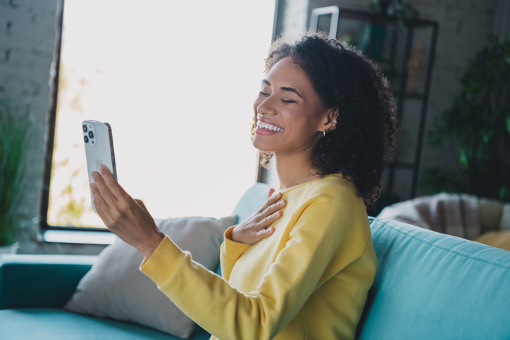 한 여자가 미소를 지으며 휴대폰을 봅니다.